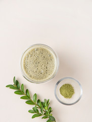 fresh matcha tea in a clear glass with flowers on yelow background. Trendy,vegan, diet drink