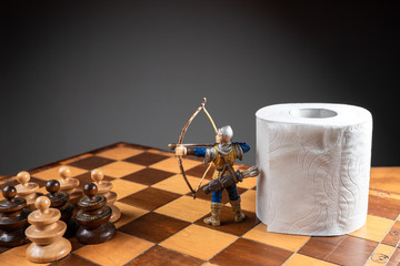 Archer defending a roll of toilet paper from an army of pawns on a chessboard. Conceptual image...