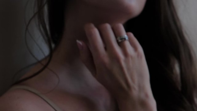Blurry video. The girl with the stings on her hands touches her hair and neck close-up.