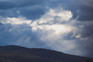 Australian mountain landscape with clouds and intense sunrays, shot in Tasmania over Mount Wellington