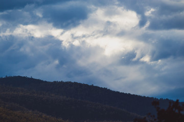 Australian mountain landscape with clouds and intense sunrays, shot in Tasmania over Mount Wellington