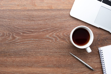 Wood office desk table with laptop computer, cup of coffee and supplies. Top view with copy space, flat lay.