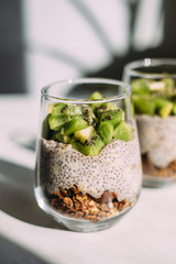 Healthy breakfast. chia pudding with kiwi and granola in glass on white background