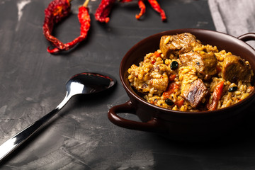 Large portion of pilaf in a clay dish. Delicious uzbek homemade meal