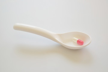 White and pink capsule or Pill in the white spoon isolated on white background. Medicine and healthy concept.