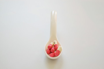 White and pink capsule or Pill in the white spoon isolated on white background. Medicine and healthy concept.