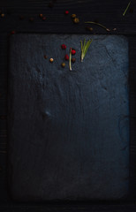 Black on black background. Spice on black stolen plate on wooden background. Place for text. Top view