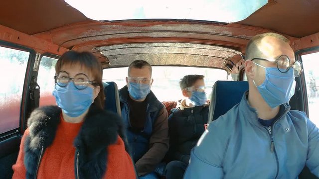 Action camera shot from inside a moving old car: a family in protective masks during an epidemic. coronavirus