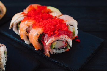 Japanese cuisine. Japanese sushi with soy sauce and wasabi on black stone plate on black background.
