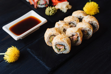 Japanese cuisine. Japanese sushi with soy sauce and wasabi on black stone plate on black background.