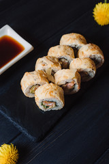 Japanese cuisine. Japanese sushi with soy sauce and wasabi on black stone plate on black background.