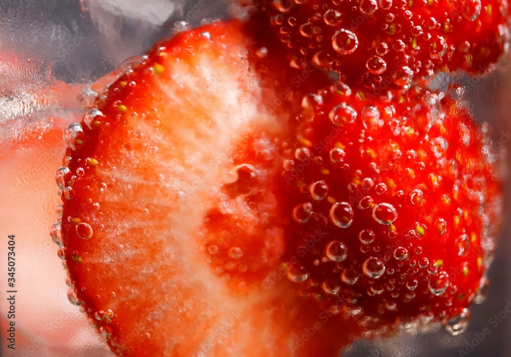 Wall mural macro closeup of isolated cocktail glass with red strawberries, sparkling tonic water and ice cubes