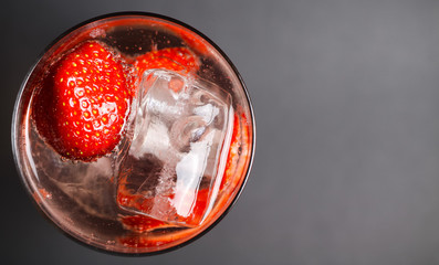 Top view close up on isolated cocktail glass with red strawberries, sparkling tonic water and ice...