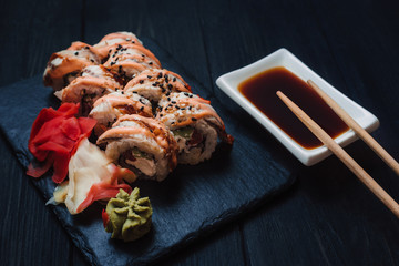Japanese cuisine. Japanese sushi with soy sauce and wasabi on black stone plate on black background.