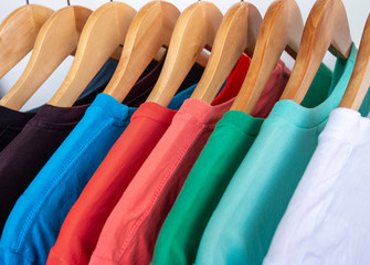 Fashion T-shirt on clothing rack - Closeup of bright colorful closet on wooden hangers in store closet.