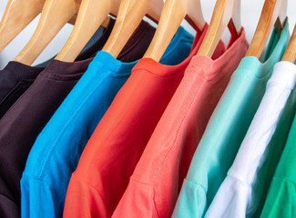 Fashion T-shirt on clothing rack - Closeup of bright colorful closet on wooden hangers in store closet.