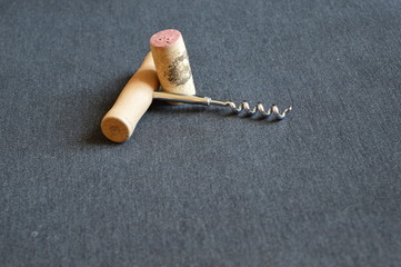 corkscrew and cork for wine on a black board