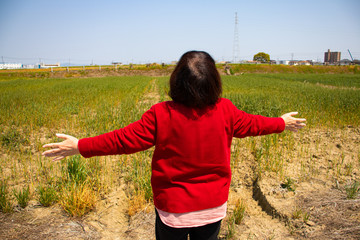 青空に向かって手を広げる高齢女性