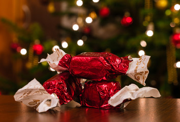 Three red Hungarian Christmas candies (szaloncukor) in front of a Christmas tree.