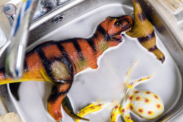 several plastic toys being washed in kitchen sink after outside kids party