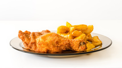 Homemade fried chicken with french fries on a glass plate.