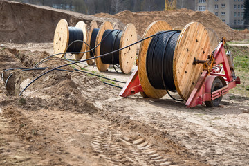 Several wooden coils with power cable laid in trench. Concept of electricity supply for...
