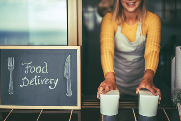 Young woman serving healthy takeaway food inside restaurant - Happy girl working inside delivery food ghost kitchen - Online business order service concept - Focus on hands