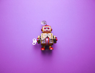 Vintage clockwork metal toy robot on the purple background. Retro toys minimal concept. Flat lay....