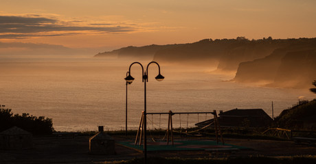 Atardecer de un acantilado con niebla y farola