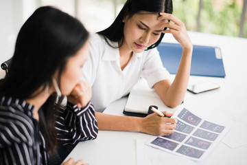 Young Asian businesswoman working with group to meeting and brainstorm which looking at paperwork felling be serious and tired. Team of business workers meeting at home office.