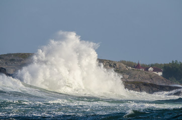 High waves hit cliffs, windy day by the sea on Sweden's west coast, Öckerö, the northern archipelago of Gothenburg.  Blue sky background with copy space and place for text.