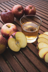 on a table freshly picked apples and a glass with fresh apple juice, near a plate with apple slices