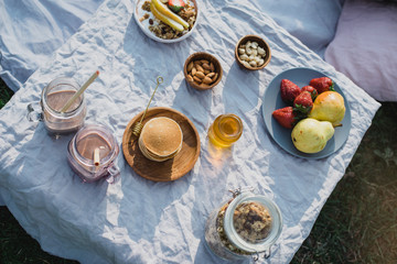 Beautiful cozy summer or spring picnic with cocoa, pancakes, honey, strawberries, pears and granola.