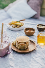 Beautiful cozy summer or spring picnic with cocoa, pancakes, honey, strawberries, pears and granola.