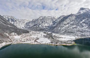 Aerial drone shot of Obertraun village in snow mountain valley by Hallstatt lake in Austria in winter