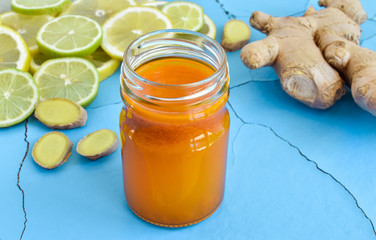 Ginger root and ginger tea, lemon and lime on a blue vintage wooden background with cracks. Seasoning, space, ingredient for tea. Concept healthy food, medicine. Close up.