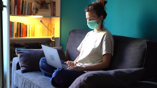 A white girl is working from home during Coronavirus or Covid-19 quarantine, coronavirus covid 19 infected patient in coronavirus covid 19 quarantine room. Logo of computer covered with mask
