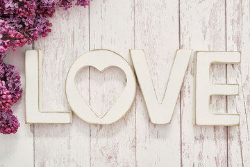 Text LOVE made from wooden letters and lilac flowers.Happy birthday greeting card. Hello spring and summer. Greeting card for Women's Day and Mother's Day.Spring season, copy space.Romantic background