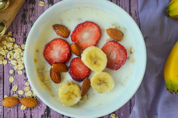 Close up porridge with milk with strawberries banana and nuts almonds