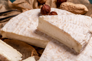 close up Tasty cheese with nuts on linen napkin wooden background copy space cheese knives. National Italian French Camembert or brie cheese