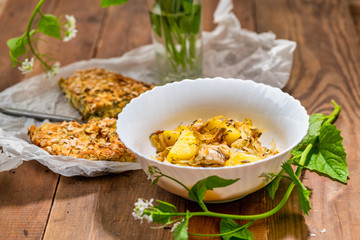 Lazy pie with cabbage and dill according to the Turkish recipe and plate of fried potatoes on a wooden table