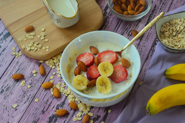 Healthy oatmeal porridge with milk decorated with pieces of fruit and berries top view