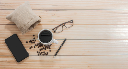 Wooden office desk with coffee cups and glasses on the side with a telephone, top view, Morning life at work concept.