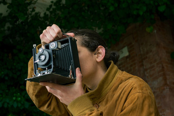 a young man takes a picture with an old camera