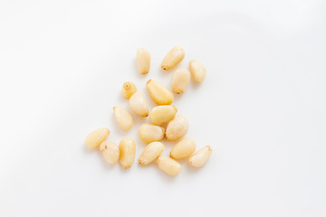 Grains of peeled pine nuts on a white background