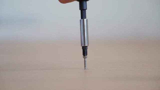 Closeup electrical screw driver un-tighten screw from wood, Removing screw or uninstalling home furniture