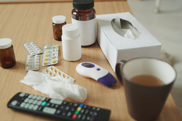 Group of plastic and glass bottles with pills and blisters with tablets on table