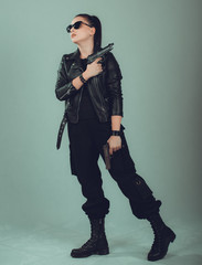 Naklejka premium Shot of a sexy military woman posing with guns,in a black jacket,black glasses in the eyes