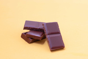 Pieces of milk chocolate on a yellow background. Broken chocolate bar