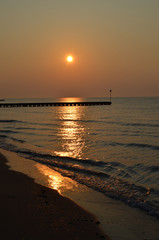 Beautiful coastline of the Adriatic Sea. Sunset on the beach of Lido di Jesolo. Piers in the sea